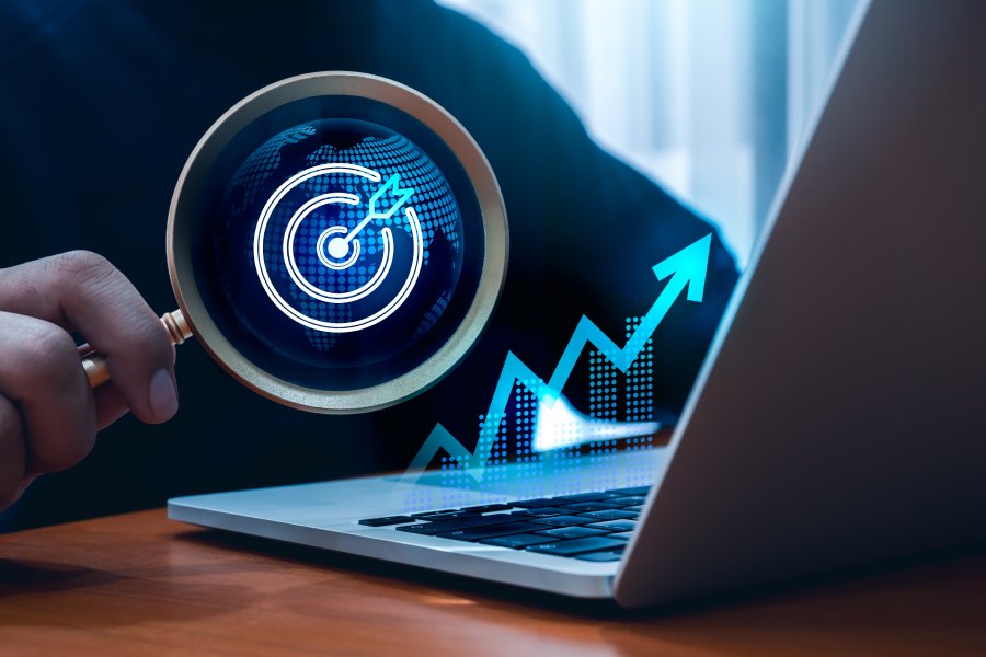 AI technology, global trends, digital marketing business search, investment online concept. Target icon with world graphic in magnifying glass lens in hand, growth graph hologram on laptop computer.